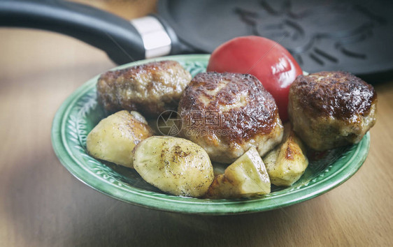 桌子上摆着一块烧肉丸和烤香味土豆片的陶瓷板图片