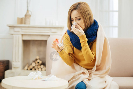 心情不好的金发年轻女子发烧擤鼻涕拿着药图片