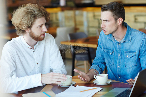 两位创意专家在咖啡馆喝茶讨论新项目图片