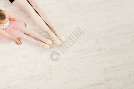 小女孩和年轻的芭蕾舞演员腿在白色木地板上的足尖鞋图片