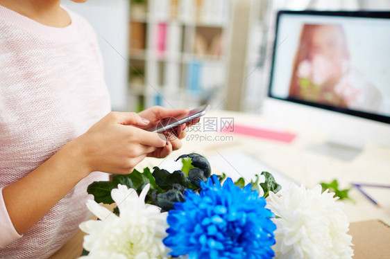 拥有现代智能手机和拨号商业伙伴号码的花卉设计师的女掌手图片