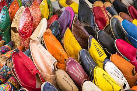 五颜六色的摩洛哥鞋在商店里对齐集市上的东方鞋多彩姿的摩洛哥拖鞋马拉喀什露天市场出售的背景图片