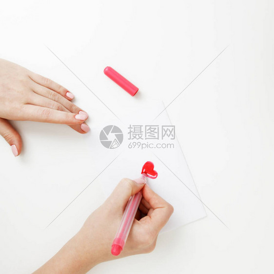 平躺顶视图在圣情人节写情书的女孩之手与红色心形图的手工制作的明信片女人在2月14日节庆祝的图片