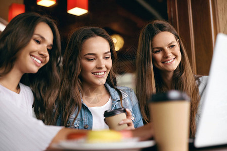 咖啡馆的女孩使用计算机的快乐朋友美丽的微笑女朋友开会喝咖啡图片