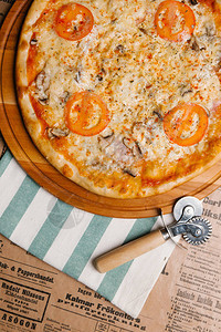 木托盘上配有西红柿火腿和蘑菇的奶酪披萨图片