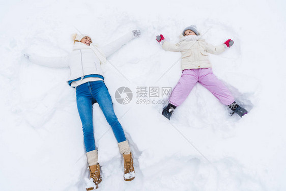 快乐的母亲和女儿的高角度视角造雪天使图片