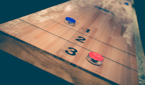 老式洗牌棋盘游戏与木制洗牌桌上的红色和蓝色圆盘具有选择焦点的图片