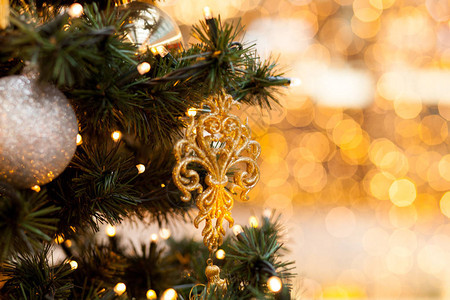 绿色树枝上的圣诞装饰品新年球和花环的符号在模糊的黄色背景上图片