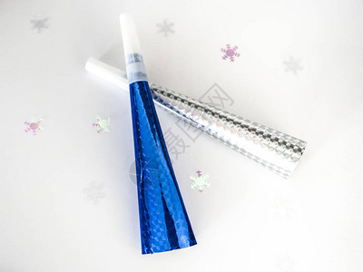 蓝色和银色全息纸和塑料除夕庆祝喇叭的特写照片在白色背景上与雪花五彩图片