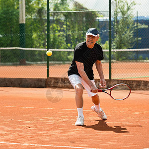 老人在网球场上击球图片