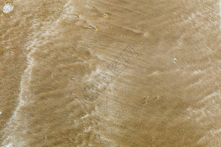 背景海浪离开后沙滩上的沙子图片