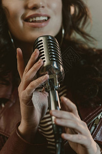 女歌手用老式麦克风演唱歌曲的裁剪镜头图片