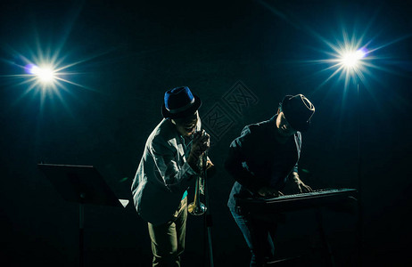 音乐家Duo乐队演奏键盘和在黑色背景下唱歌图片