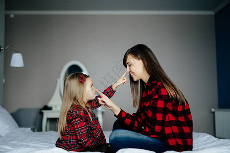 母亲及其女儿孩在床上玩耍和触摸对方的鼻子图片