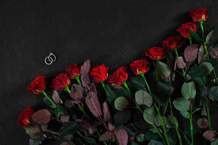 黑色背景的红玫瑰花束和戒指图片