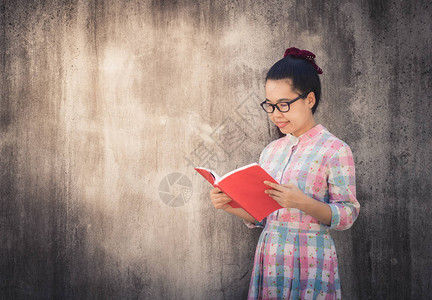 教育和知识概念美丽的亚洲年轻女阅读深水泥墙背景书籍图片