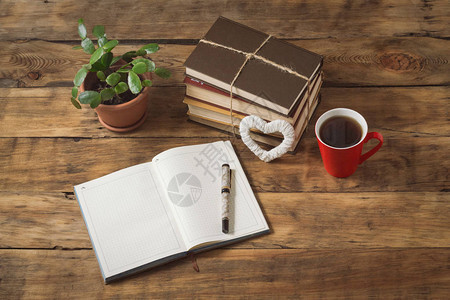 日记心脏花朵书卷红杯加咖啡或茶木制桌上的笔照片背景图片
