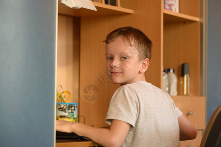 儿童房间里一个男孩在工作场所用电脑的肖像图片