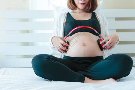 坐在床上的快乐亚洲孕妇戴图片