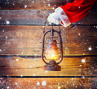 圣诞老人手拿着老式油灯在木制背景图片