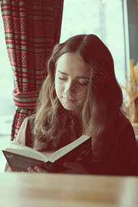 一位勤奋的女学生在靠窗的咖啡馆里看书图片