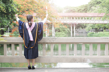 快乐和高兴的毕业亚洲女学生站着举手图片