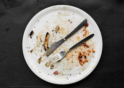 黑 车白色陶瓷板和披萨的残渣在黑皮革面背景