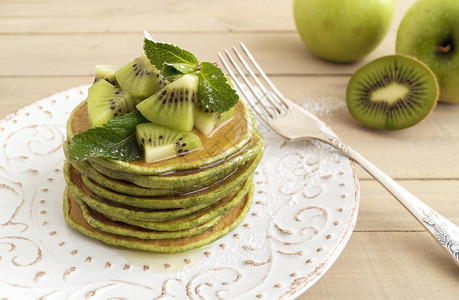绿色煎饼加蜂蜜和猕猴桃木制背景图片
