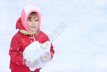 一个孩子看着镜头雪手里拿着一个雪球图片