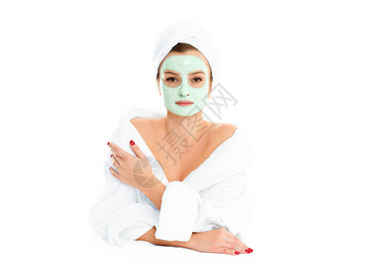 穿浴袍的漂亮女人正在得到面部粘土面具美容化妆品身体护图片