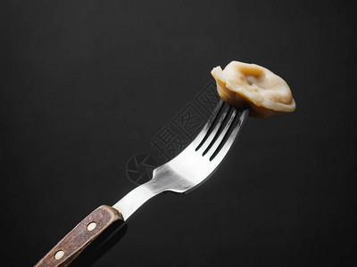 木叉上的酸奶油饺子黑色背景图片