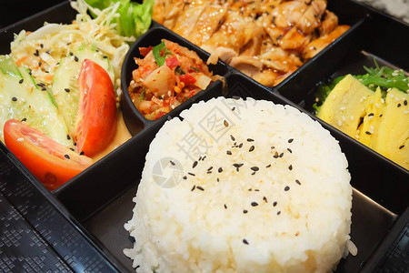 传统日本料理便当盒或多层盒配照烧鸡肉饭沙拉玉子烧或煎蛋卷日式裙带菜或海图片
