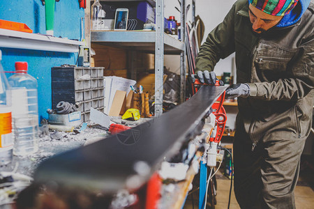滑雪服务车间的一名男工正在修理滑雪板的滑动面图片