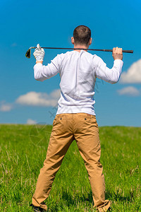 高尔夫球员用高尔夫俱乐部的肩膀在绿色田地中休图片