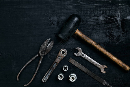 旧的生锈的工具躺在黑色的木桌上锤子凿子金属剪刀扳手顶视图复制空间图片