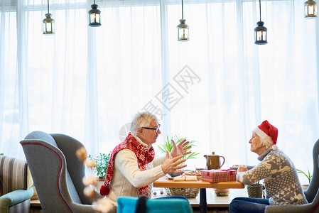 欢快的情侣坐在马特桌边共度圣诞晚宴和聊天时积极摆动复制空图片