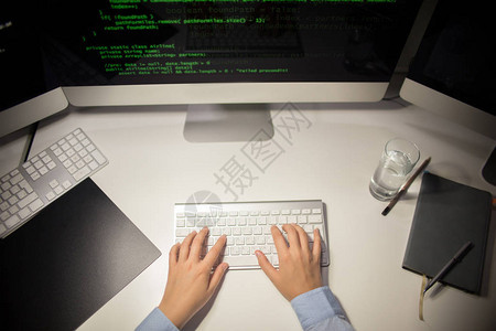 坐在办公桌前使用现代计算机编写代码的无法识别程序员图片