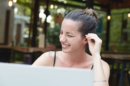 微笑满意的女肖像在笔记本电脑上与社交网络上的朋友聊天时很开心图片