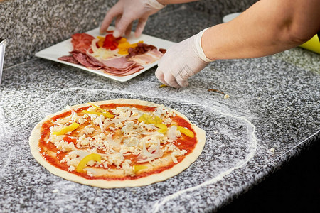 拿披萨的原料厨师用手把配料放图片