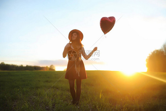 一个戴着帽子的女孩在公园散步一个提着篮子的女孩在春天散步夕阳西下图片