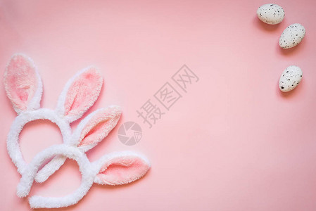 复活节鸡蛋和两只白毛兔子耳朵的顶端景色在粉红色背景图片