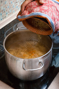 煮汤厨师将炖好的酸菜从陶瓷锅中放入带有肉图片