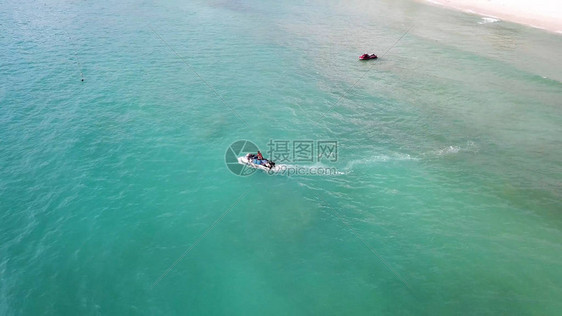 白色沙滩和水上摩托艇在蓝色泻湖水上的鸟瞰图在绿松石清澈的海水中高速巡航的喷气式滑图片