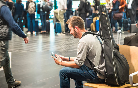 国际机场的潮人使用移动智能手机图片