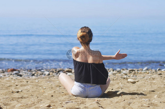年轻女子在海洋滩上以莲花姿势冥想图片