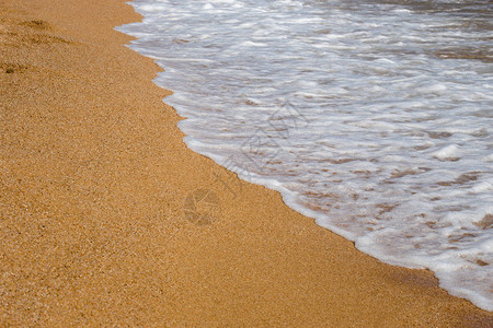 海滩度假和旅游的概念海浪的背景特写镜头与黄色沙滩上的泡沫在西图片