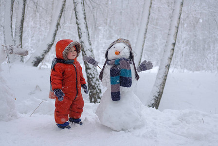 冬日雪地里可爱的欧洲男孩和雪地树林图片