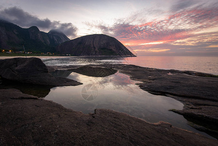 日落时在水中反射的岩石山图片