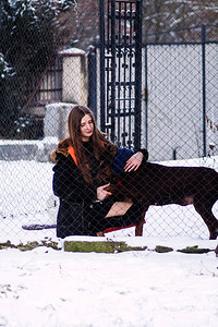 一个小女孩去笼子里去找杜宾犬的老狗寒冷天气的冬天复制空间图片
