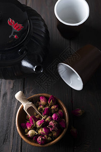 木碗上的玫瑰花芽茶黑木背景图片